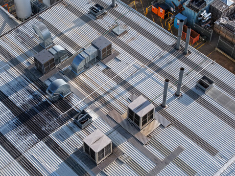Aerial view of industrial factory roof with metal corrugated sheets, ventilation units, and exhaust pipes in Kilsyth South, Melbourne, VIC, Australia.