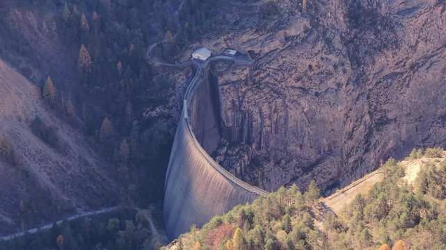 Aerial view of the historic Vajont Dam nestled within the steep rocky canyon walls and surrounding forest in Pordenone, Friuli-Venezia Giulia, Italy.