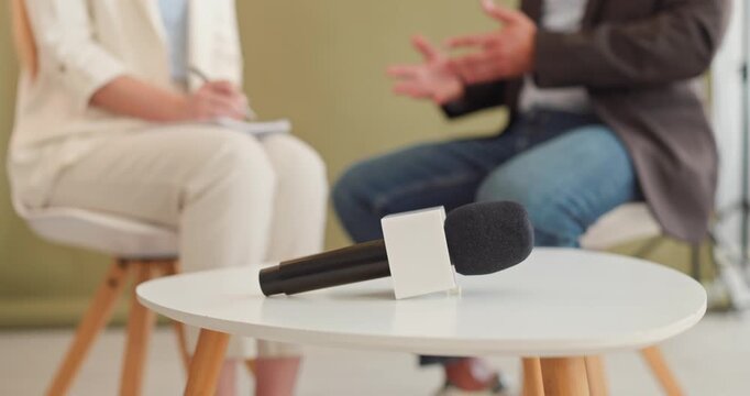 Microphone for interview between journalist and guest. Shot in a studio with soft blur, reporter and guest converse, for media, recording and broadcast needs. Symbol of conversation and talk.