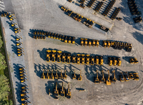 Aerial view of rows of yellow construction machinery and excavators parked in a large storage yard near Noxon Road in LaGrange, New York, United States.