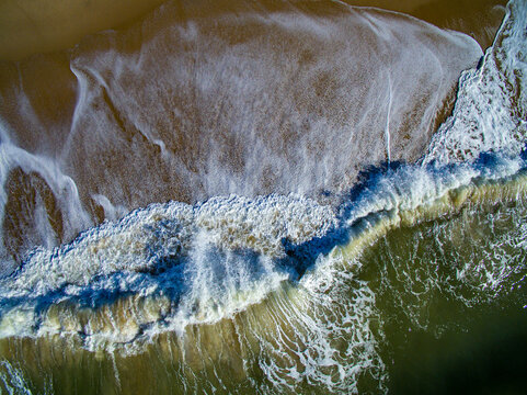Aerial view of crashing waves at Katama Beach, showing the contrast between the sandy shoreline and the deep ocean water in Edgartown, Massachusetts, United States.