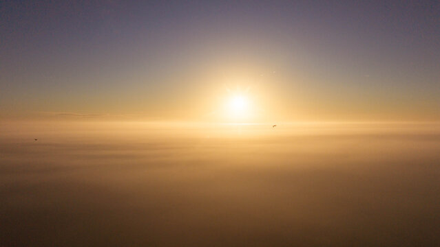Aerial view of a golden sunrise breaking through a thick layer of clouds above the landscape in Salisbury, England, United Kingdom.