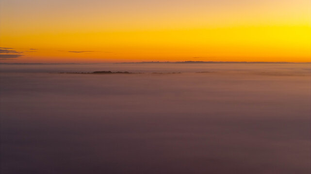 Aerial view of Stonehenge emerging from a thick layer of morning fog at sunrise in Salisbury, England, United Kingdom.