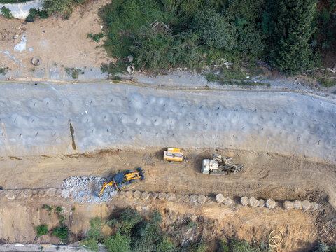 Aerial view of construction machinery working on a soil stabilization project with a concrete retaining wall in Istanbul, Istanbul, Turkiye.