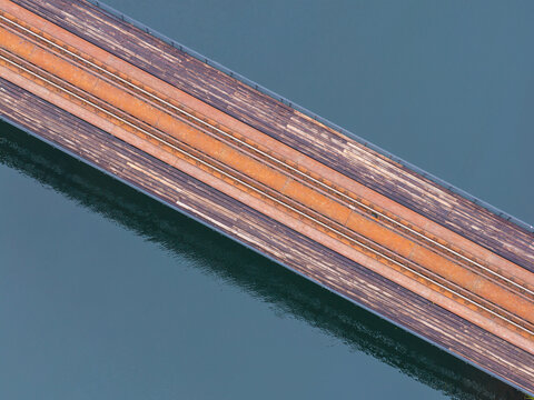 Aerial view of the historic railway truss bridge with weathered wooden planks and rusted metal tracks over water in Rutki, Pomeranian Voivodeshi, Poland.