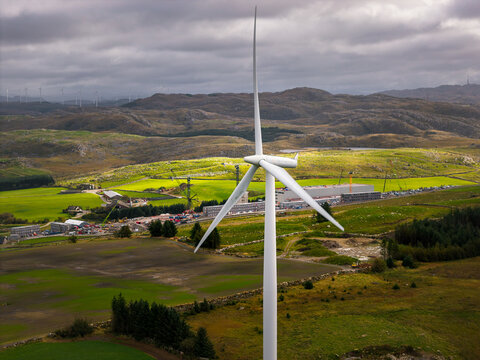 Aerial view of a wind turbine at the Green Mountain SVG-Undheim Datasenter construction site surrounded by rolling green hills and fields in Undheim, Rogaland, Norway.