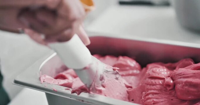 Close Up of Creamy Pink Strawberry Gelato Being Scooped with a Spatula from a Metal Container in a Professional Ice Cream Shop