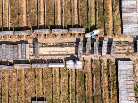 Aerial view of workers drying noodles on wooden racks in an outdoor field in Polanharjo, Central Java, Indonesia.