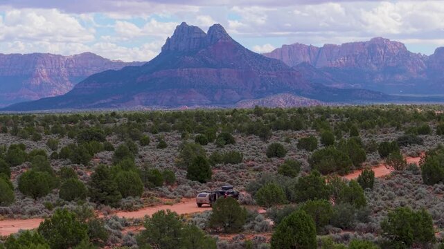 Aerial view of SUV pulling a teardrop camper trailer overland on Gooseberry Mesa with the stunning backdrop of Zion National Park.