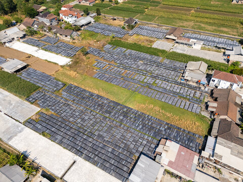 Aerial view of UKM Sohun production facility with rows of drying sohun noodles on trays in an open field near residential houses in Polanharjo, Central Java, Indonesia.