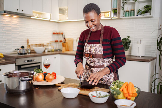 Happy black woman cooking healthy meal in modern kitchen