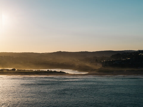 Aerial view of the coastal landscape at Dee Why featuring the lagoon meeting the ocean under a soft golden sunset light with rolling hills in the background Dee Why, New South Wales, Australia.