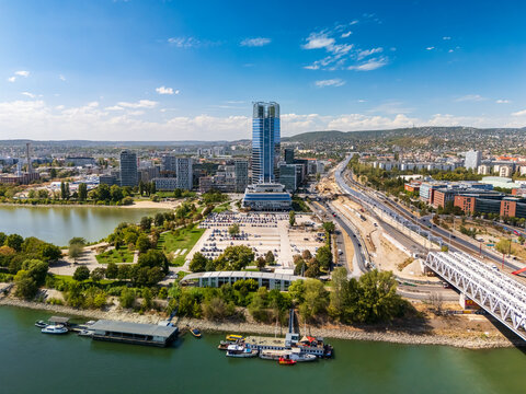 Aerial view of Mol Tower and Budapest skyline along the Danube riverbank, with modern office buildings, bridges, roads, and urban parks in the Hungarian capital.