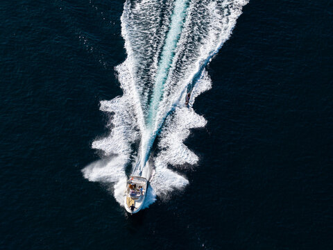 Aerial view of a motorboat cruising through deep blue Mediterranean waters, leaving a long white wake behind it in Antibes, Provence-Alpes-Cote d'Azur, France.