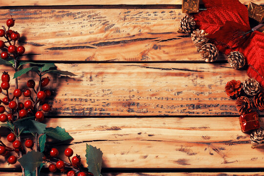 Rustic wooden table Christmas background framed with pine cones and small gifts, with ample space for text.