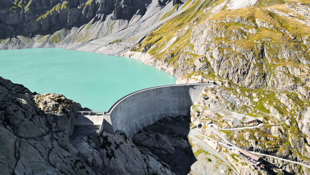 Aerial view of the Vieux Emosson dam and turquoise lake nestled in the rugged rocky mountains of the Swiss Alps in Finhaut, Valais, Switzerland.