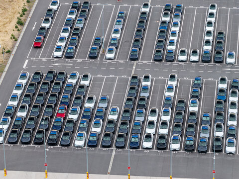 Aerial view of Tesla Gigafactory Berlin-Brandenburg parking lot filled with rows of new electric vehicles, showcasing industrial logistics in Grunheide Mark, Brandenburg, Germany.