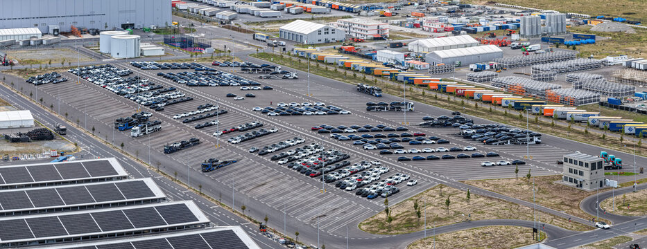 Aerial view of Tesla Gigafactory Berlin-Brandenburg showing rows of parked electric vehicles and transport trucks in the logistics yard in Grunheide Mark, Brandenburg, Germany.