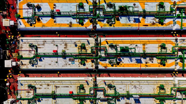 Aerial view of the industrial deck of a cargo ship featuring complex piping systems, storage tanks, and vibrant yellow markings in Smederevo, Podunavlje District, Serbia.