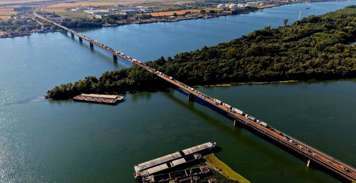 Aerial view of the Smederevo bridge crossing the Danube river with cargo barges at the nearby shipyard and traffic flowing across the structure in Smederevo, Podunavlje District, Serbia.
