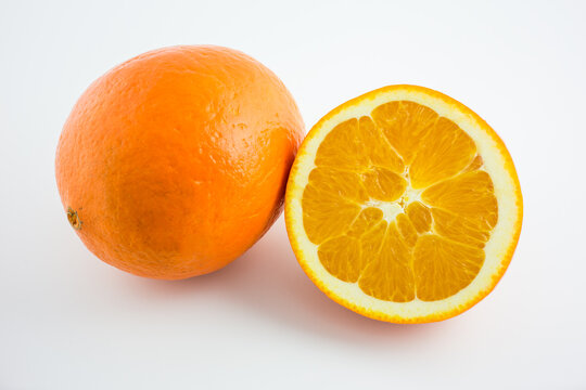 A whole fresh orange and a sliced half orange displayed on a plain white background, showing its peel and inner segments.