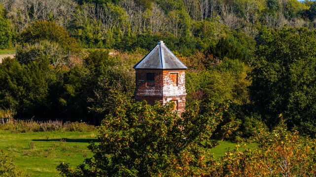 Aerial view of the historic Pepperbox Folly tower surrounded by dense woodland and green fields at Pepperbox Hill in Salisbury, England, United Kingdom.