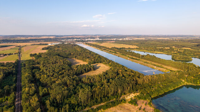 Aerial view of Labe Arena Racice surrounded by lush forests, agricultural fields, and calm water bodies in Racice, Ustecky kraj, Czechia.