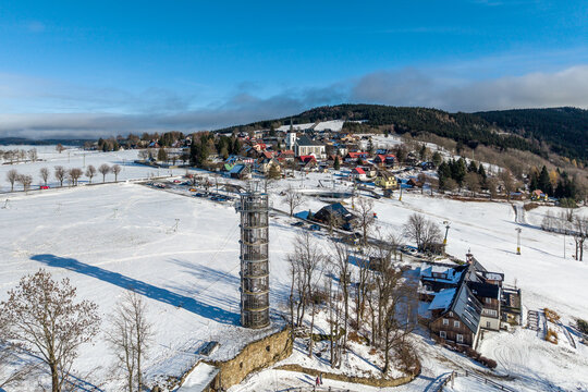 Aerial view of Majak Jary Cimrmana surrounded by snow-covered fields and the village of Korenov in the Liberecky kraj, Czechia.