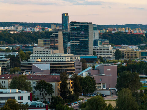 Aerial view of the modern skyline featuring glass skyscrapers and office buildings surrounded by lush green trees in the city of Vilnius, Vilnius County, Lithuania.