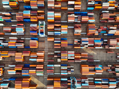 Aerial view of the semi-automated container port with rows of colorful shipping containers and automated storage yard in Vado Ligure, Liguria, Italy.