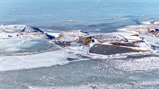 Aerial view of ice floes and frozen water surface with cracked patterns and snow-covered textures in Latvija.