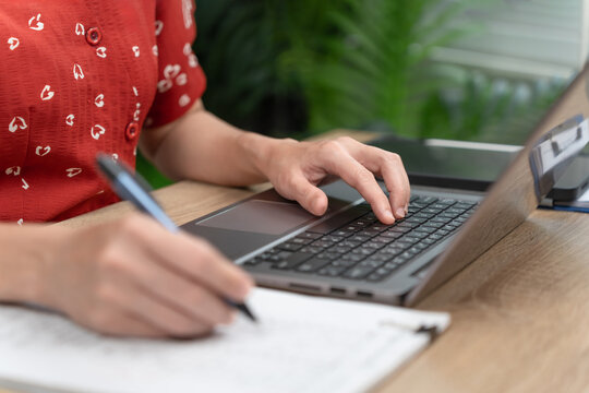 Female office worker reviewing documents and using a laptop to record, managing digital information, Representing document verification, Data entry and efficient office administration, Modern office