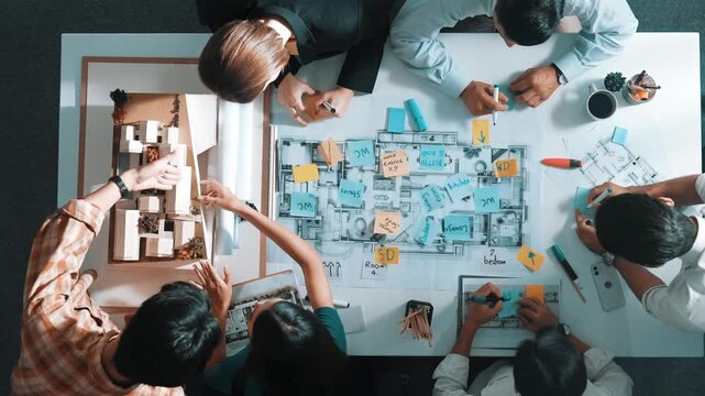 Top aerial view of project manager or civil engineer writing at blueprint and planning building design. Aerial view of architect working together at meeting table with document placed. Alimentation.