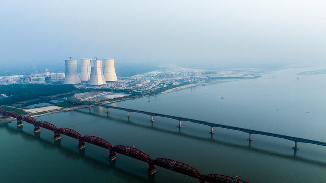 Aerial view of the Rooppur Nuclear Power Plant with cooling towers along the Padma River, featuring the historic Hardinge Bridge and Lalon Shah Bridge in Pabna, Rajshahi Division, Bangladesh.