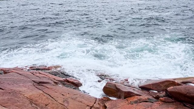 ocean waves crashing on red rocks at green cove nova scotia