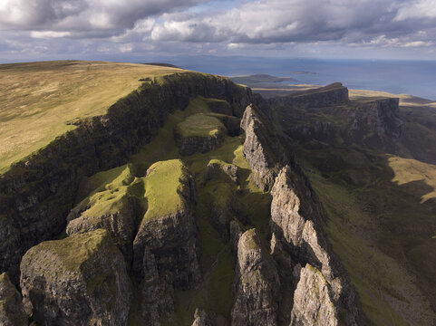 Aerial view of the Quiraing, a dramatic landslip on the Isle of Skye featuring rugged rock formations and grassy slopes under a cloudy sky in Scotland, United Kingdom.