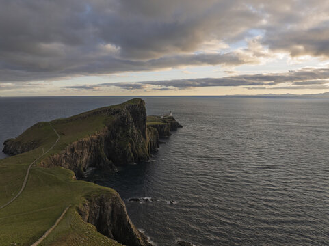Aerial view of Neist Point Lighthouse perched on dramatic cliffs overlooking the sea in Scotland, United Kingdom.