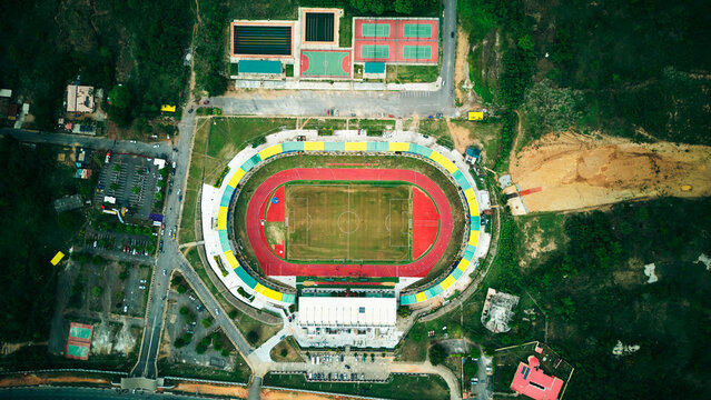 Aerial view of MKO Abiola Stadium featuring a football pitch and running track surrounded by tennis courts and parking facilities in Abeokuta, Ogun State, Nigeria.
