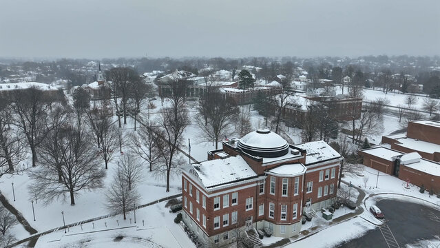Aerial view of the snow-covered campus featuring historic brick buildings and a prominent domed structure amidst bare trees under a winter sky in Lynchburg, Virginia, United States.