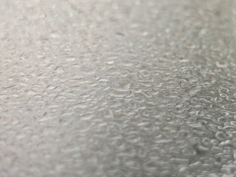 Extreme close-up macro photography of condensed water droplets forming natural patterns on a frosted textured surface. Features a shallow depth of field with soft bokeh, highlighting the pure, fresh