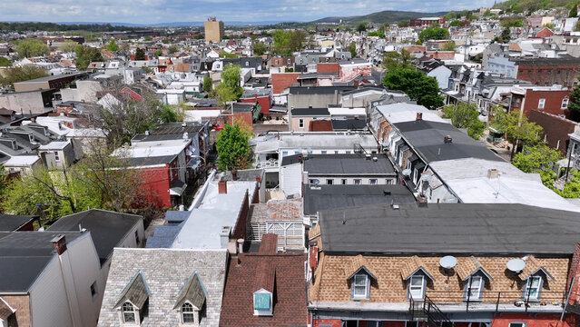 Aerial view of the dense residential neighborhood with rows of houses, varied rooftops, and lush green trees in Reading, Pennsylvania, United States.