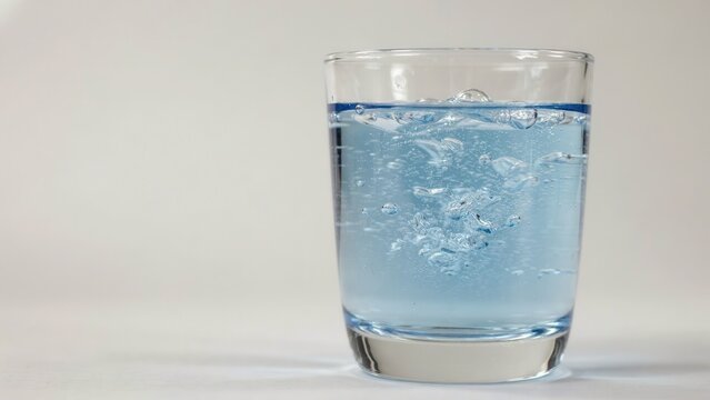A glass of carbonated blue liquid with bubbles isolated on white background. Perfect for refreshing drink advertisements or beverage industry marketing.