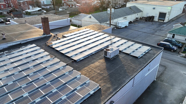 Aerial view of solar panels installed on a flat commercial rooftop during sunset in Columbia, Pennsylvania, United States.