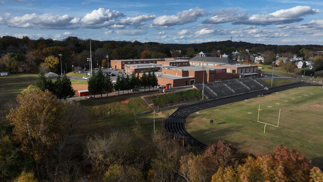 Aerial view of the Altavista High School complex with a football field, running track, and red brick buildings surrounded by autumn trees in Altavista, Virginia, United States.