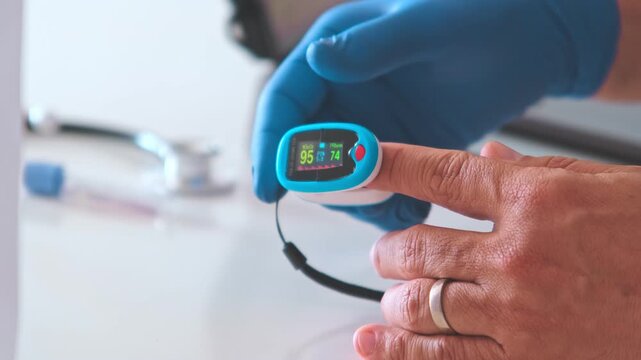 Medical professional removing a pulse oximeter from a male patient's finger after a check-up