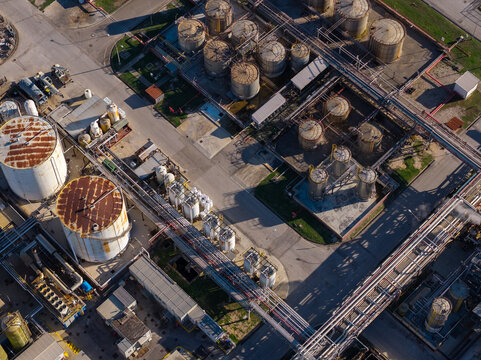 Aerial view of an industrial facility featuring numerous large storage tanks, complex pipeline networks, and paved access roads in Nera Montoro, Umbria, Italy.