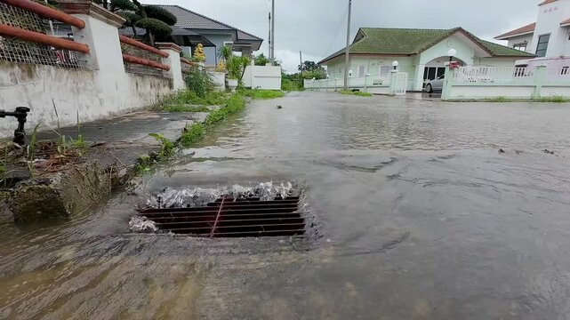 Water during a rainstorm flows into the drainage grate. Rainwater flowing down the impervious pavement to the storm drain equipped with cast iron grid during a rain