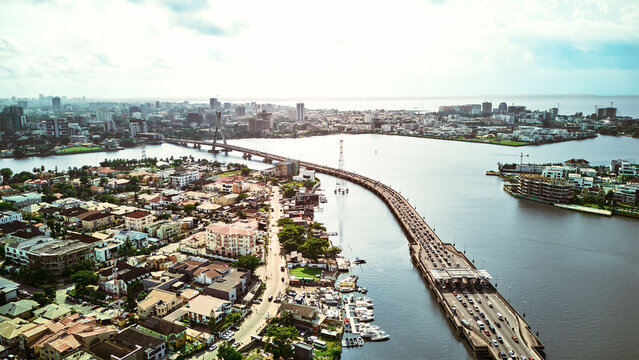 Aerial view of the Lekki-Ikoyi Link Bridge spanning the lagoon with heavy traffic, surrounded by urban residential areas and waterfronts in Lagos, Lagos, Nigeria.