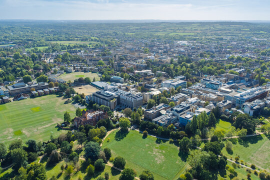 Aerial view of the University of Oxford campus featuring modern data center buildings, historic architecture, expansive green playing fields, and lush trees in Oxford, England, United Kingdom.
