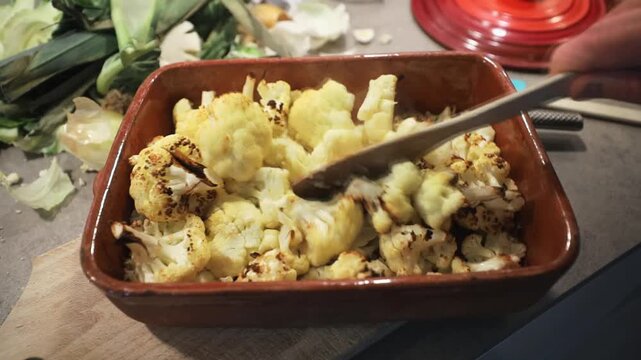 Stockholm, Sweden A cook mixes grilled cauliflower florets with a wooden utensil in an earthenware dish.